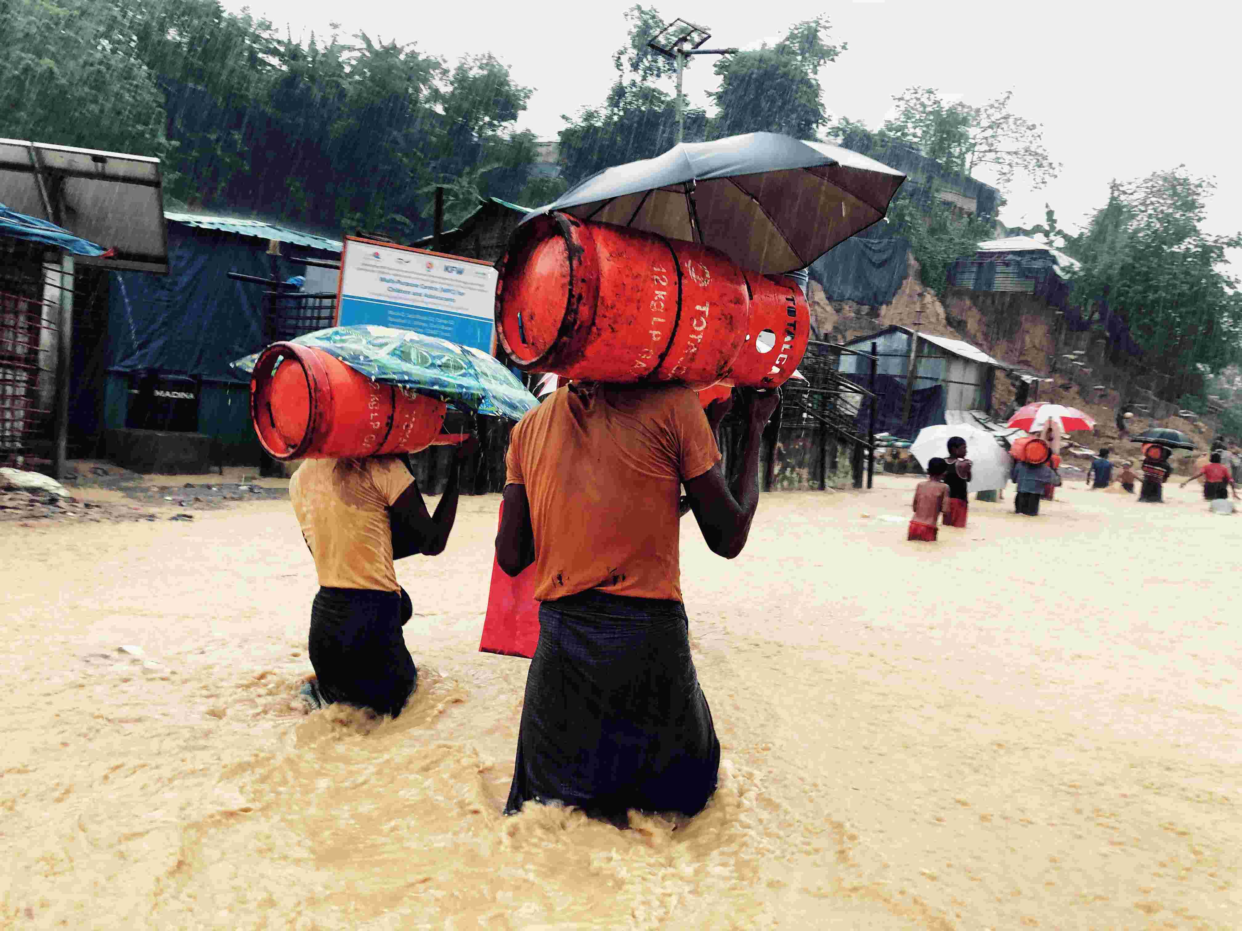 വെള്ളം ഉയര്ന്നുതുടങ്ങിയതിനു പിന്നാലെ പാചക വാതക സിലിണ്ടറുകളുമായി സുരക്ഷിത കേന്ദ്രത്തിലേക്ക് പോവുന്ന റോഹിന്ഗ്യകള്